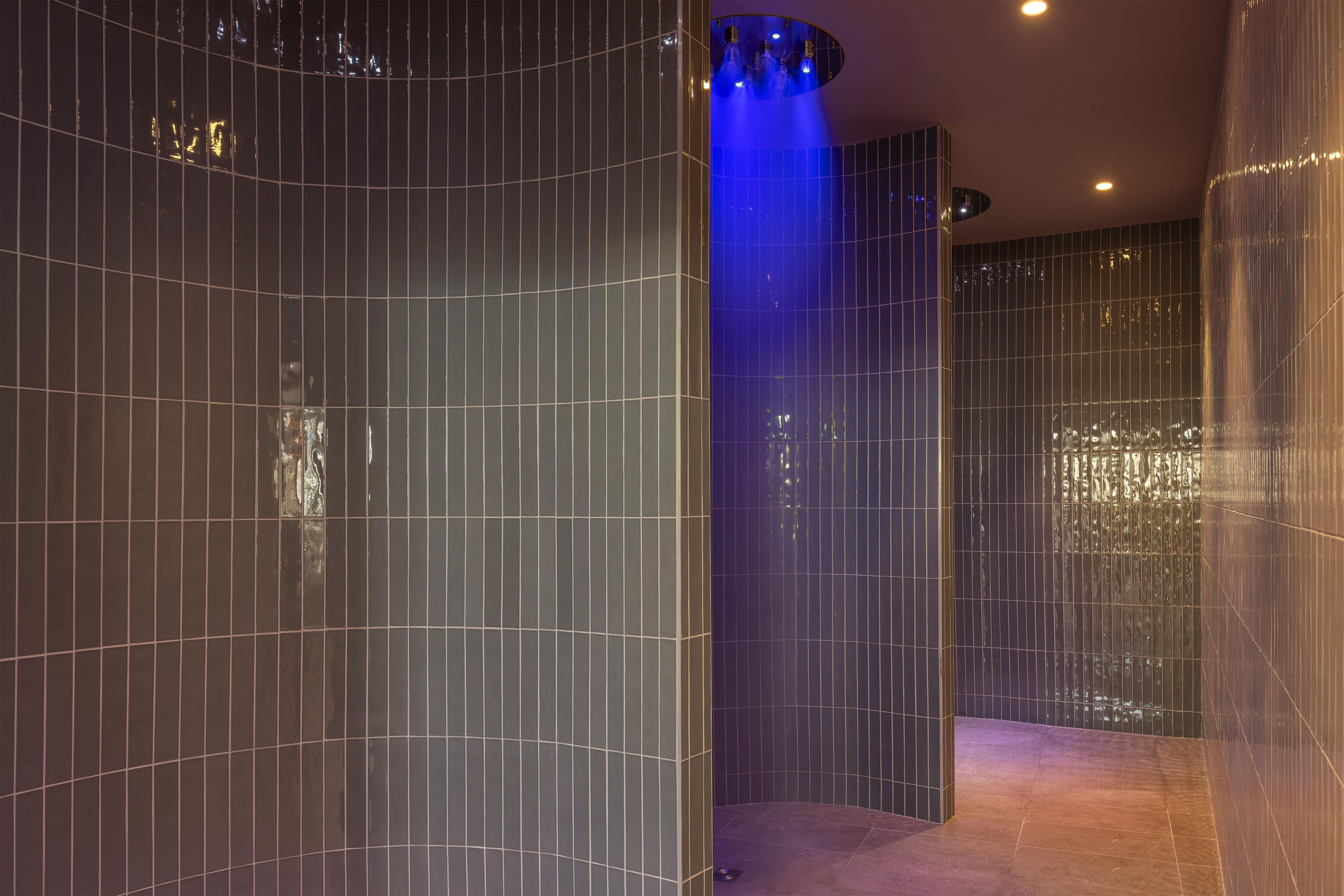 Ein modernes Interieur mit geschwungener Wandgestaltung, blauer Lichtakzentuierung und einer reflektierenden Oberfläche.