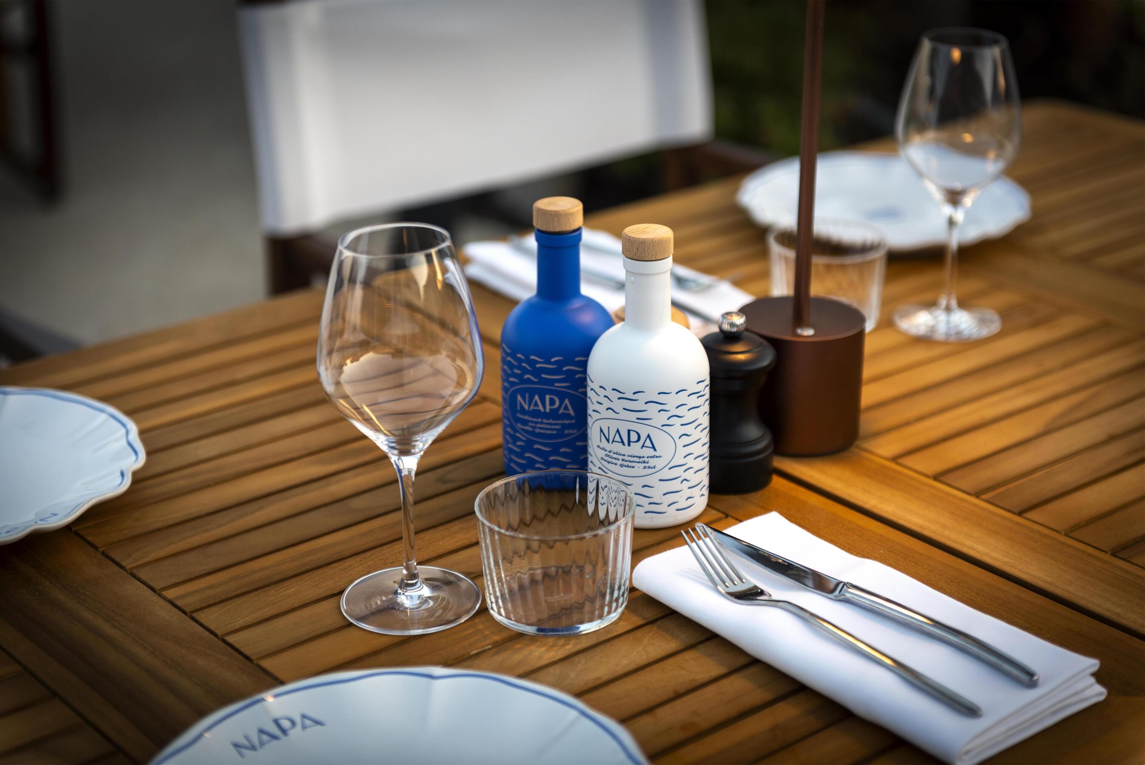 Une table dressée pour le dîner, avec des verres à vin, une bouteille de vin de Napa, un verre d’eau et un salier et un poivrier.