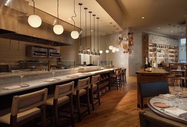 A modern bar area with a long counter, multiple bar stools, hanging spherical pendant lights, and a wine rack. - The Ava Hotel Paso Robles, Curio Collection By Hilton (Paso Robles)