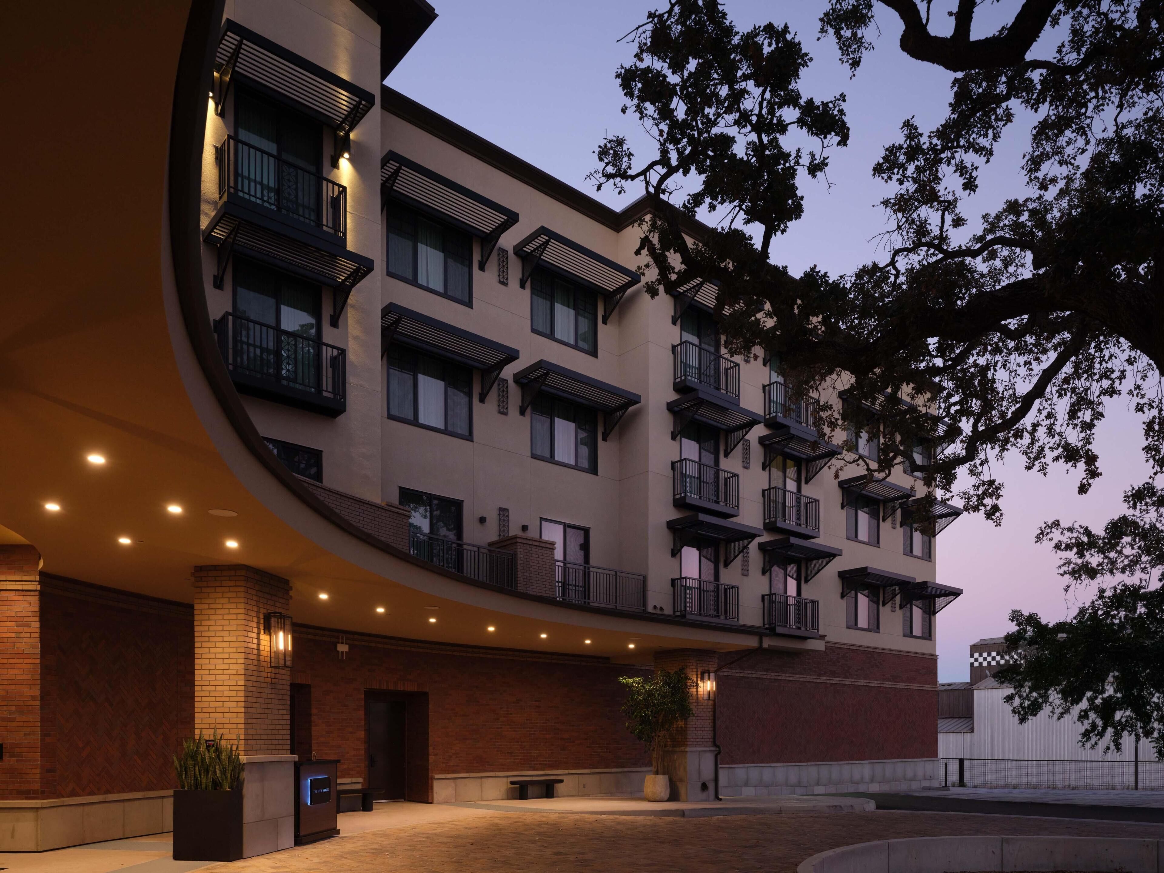 A modern building with multiple balconies, a brick facade, and a curved entrance.
