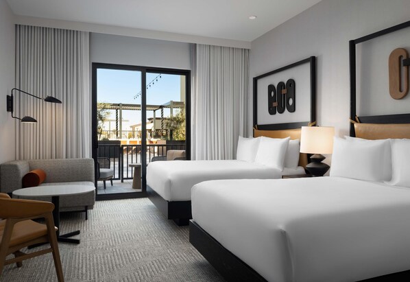 A hotel room with two beds, a sofa, a small table, and a view of the outside. - The Ava Hotel Paso Robles, Curio Collection By Hilton (Paso Robles)