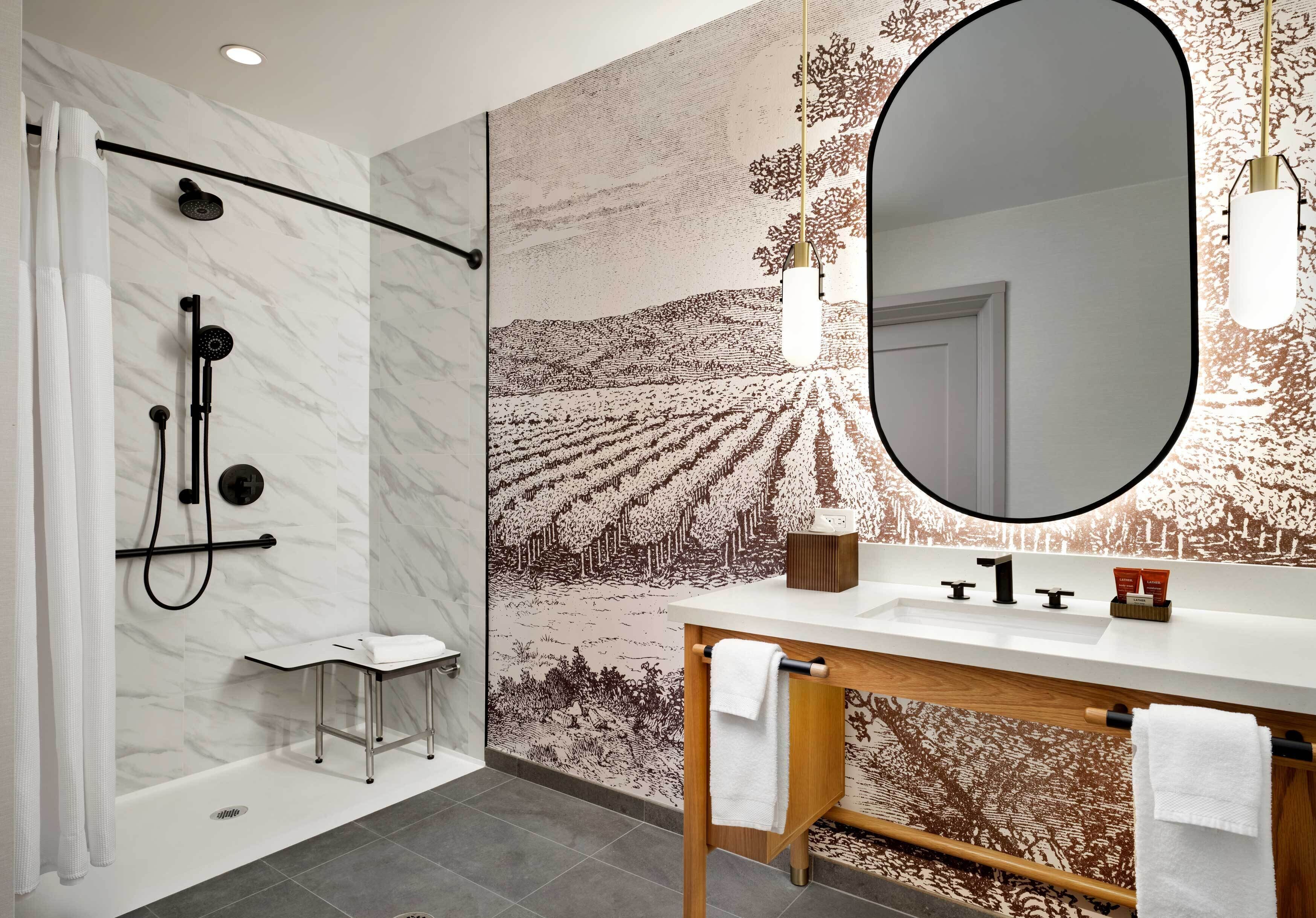 A modern bathroom with a shower, a vanity, and a large mirror.