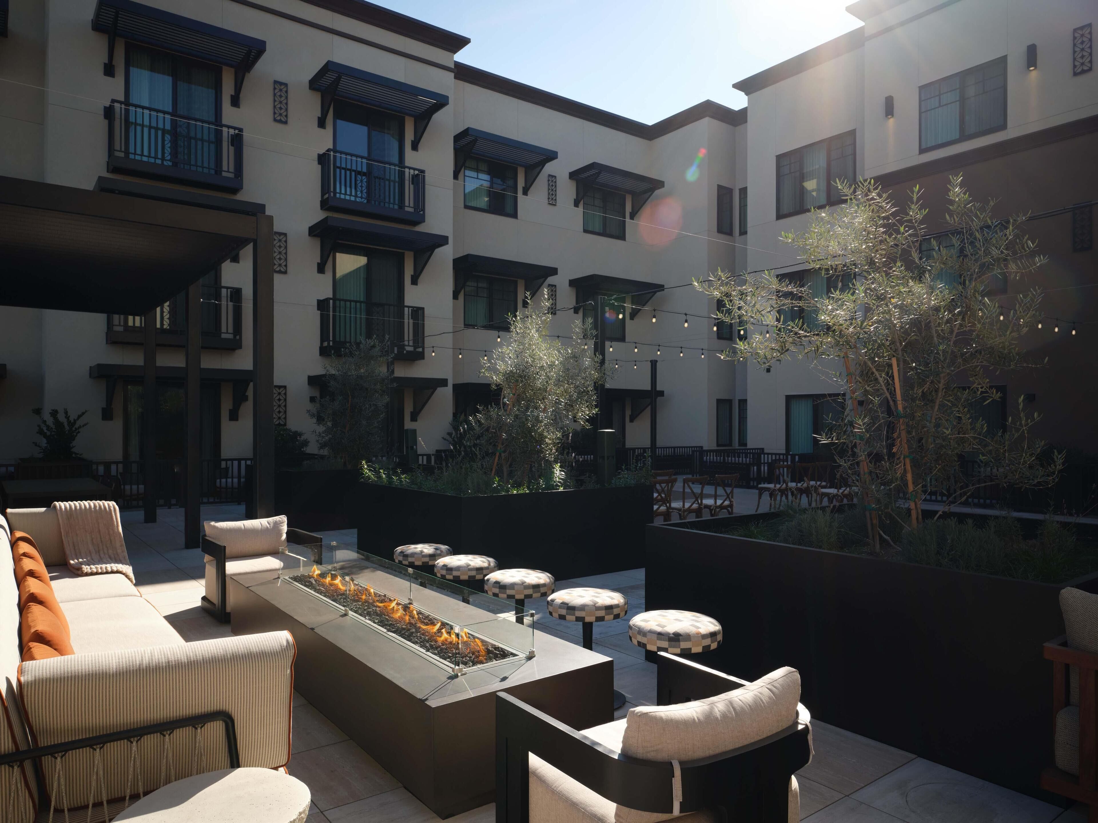A courtyard with outdoor seating, a fire feature, and a building with balconies.