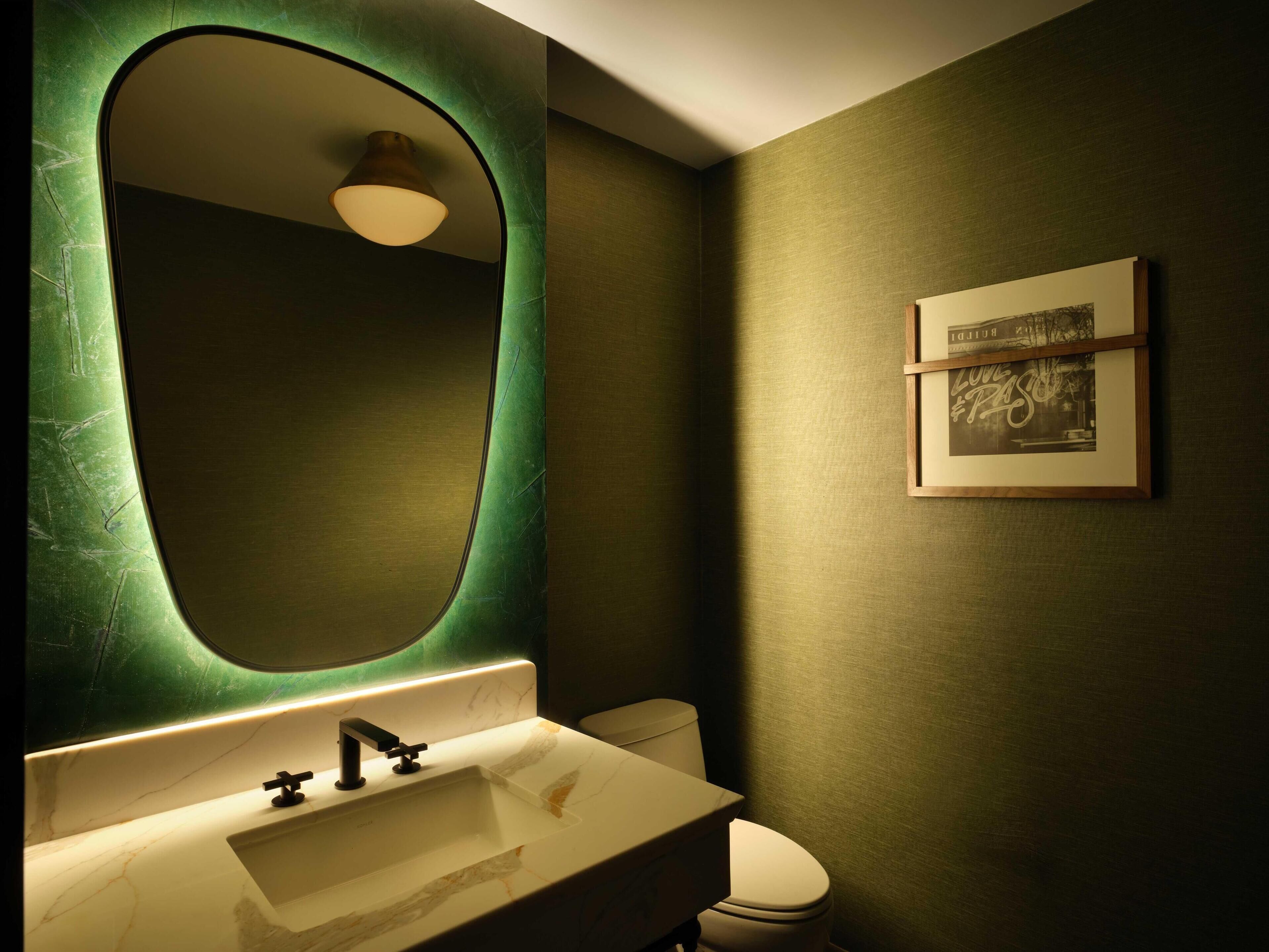 A bathroom with a marble sink, a toilet, and a framed picture on the wall.