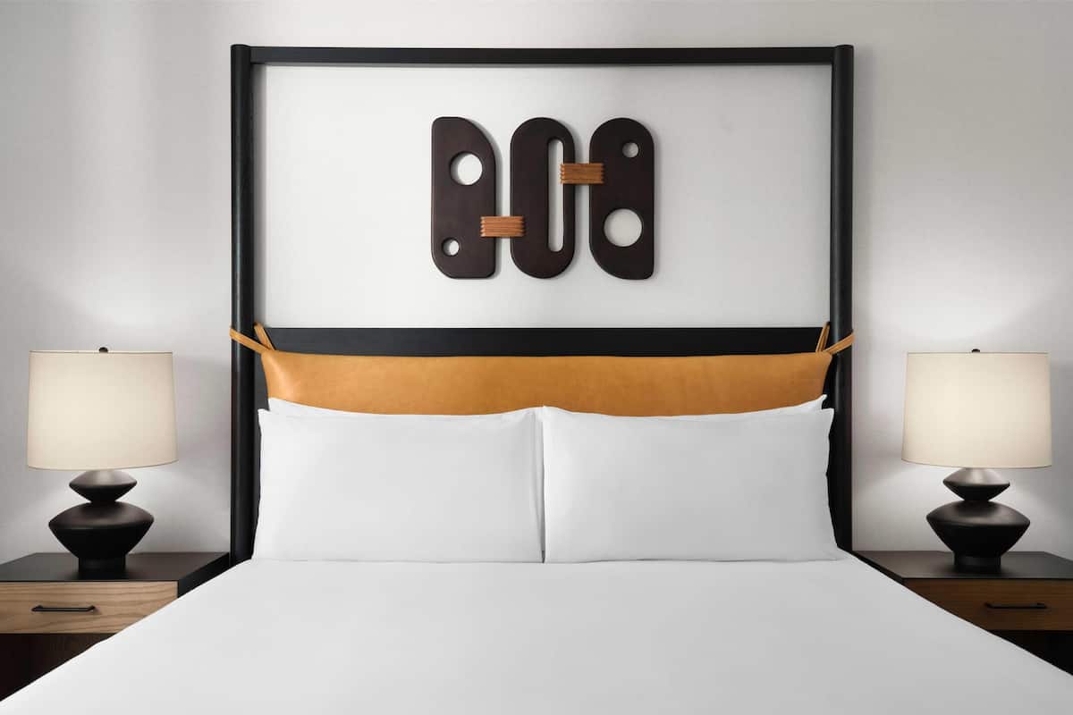A hotel room with a bed, two bedside tables with lamps, and a decorative headboard.