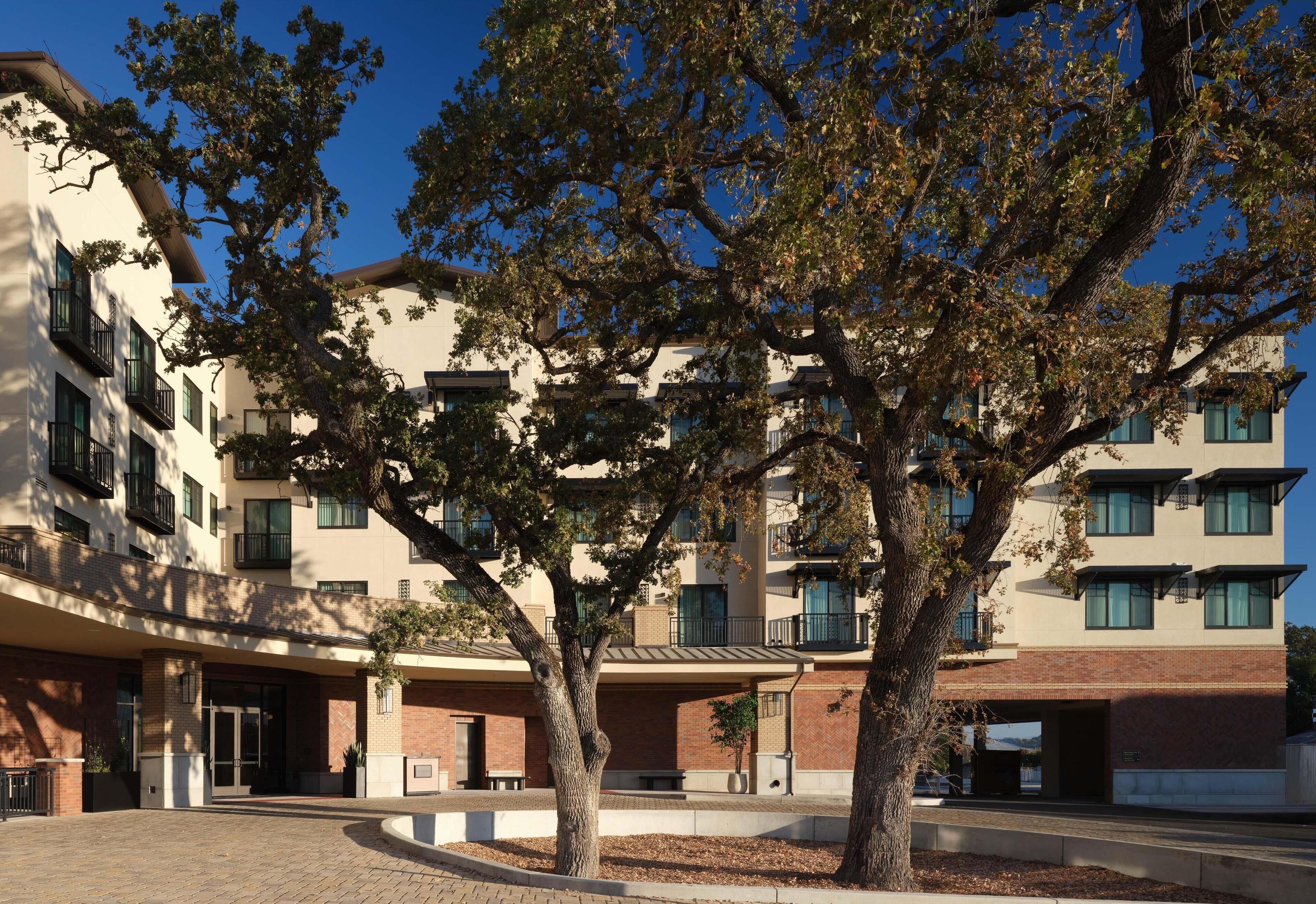 Un edificio de varios pisos con un patio central, que cuenta con un árbol grande y un paseo cubierto.