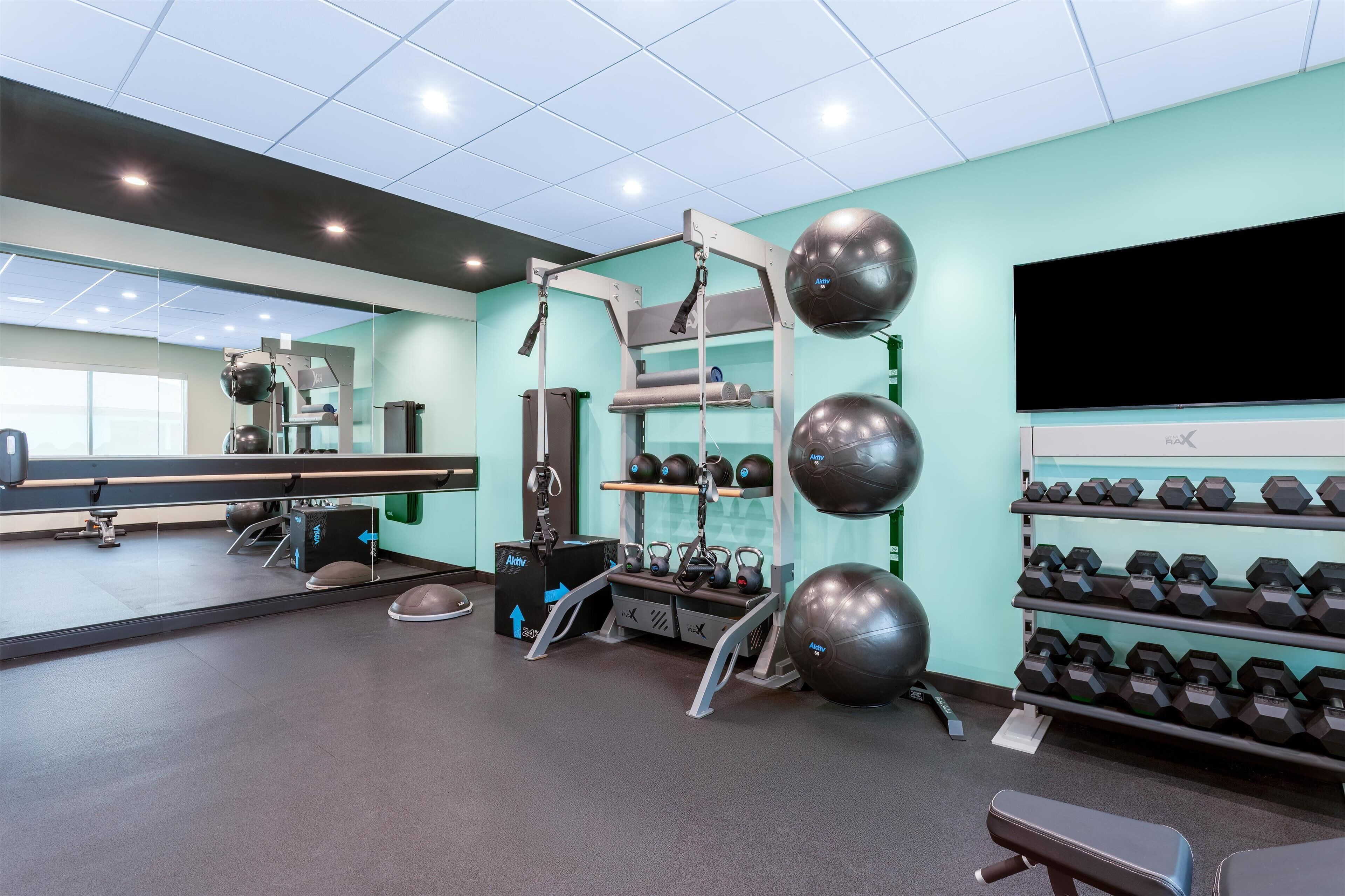 Un gimnasio con equipo de ejercicio, un espejo y un televisor.