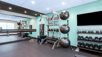 Une salle de sport équipée de matériel d’exercice, d’un miroir et d’un téléviseur.