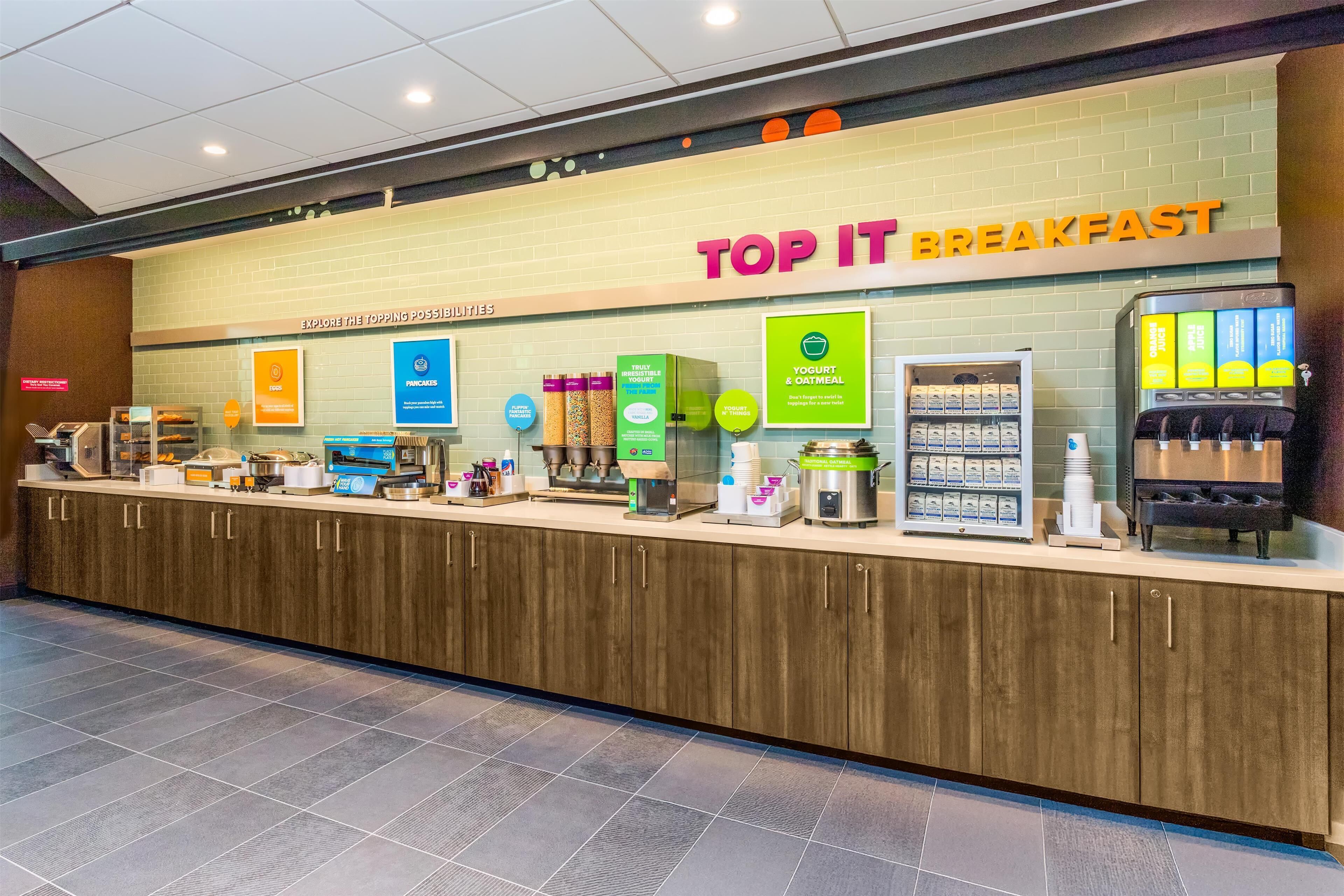 A breakfast counter with a variety of food options and a sign that reads 'TOP IT BREAKFAST'.