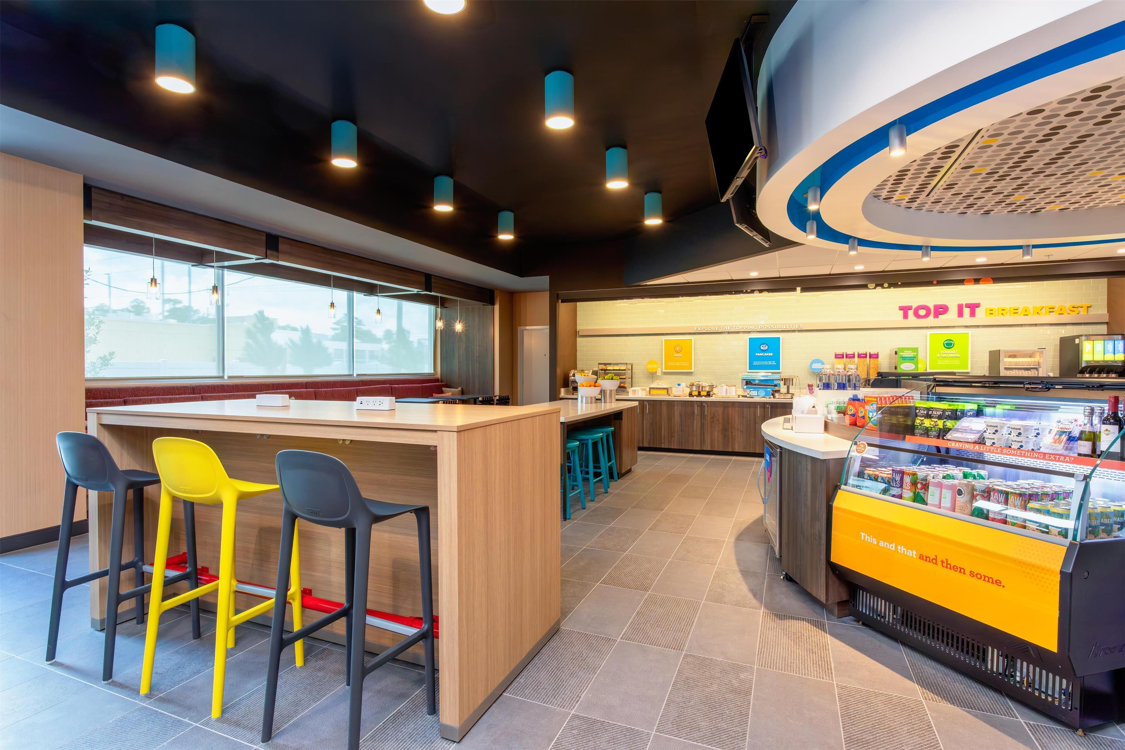 A modern breakfast area with a counter, bar stools, and a refrigerated display.