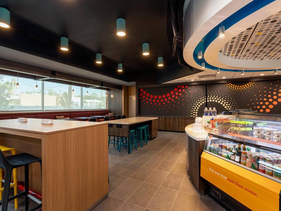 A modern cafe with a wooden counter, bar stools, and a refrigerated display case.