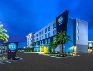 Een modern hotelgebouw met een opvallend 'tru by Hilton' bord, meerdere verdiepingen en een goed verlichte ingang.