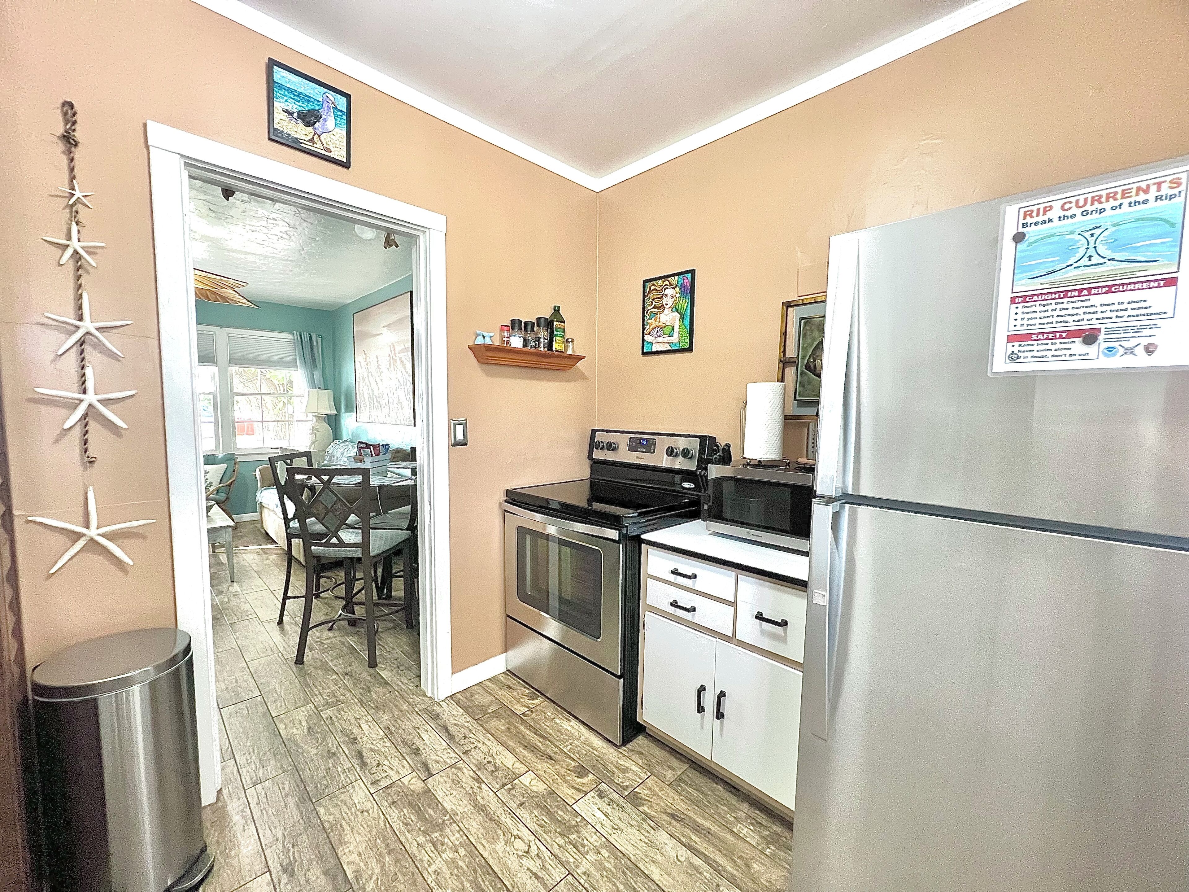 A compact kitchen with a refrigerator, stove, microwave, and a dining area with chairs and a table.