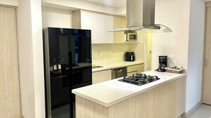 A modern kitchen with a black refrigerator, a microwave, a coffee maker, and a gas stove.