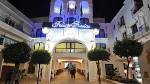A building with a sign reading "Felices Fiestas" at night, featuring a central archway and multiple balconies.