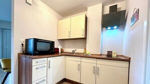 Une cuisine de taille réduite équipée d’un four à micro-ondes, d’un évier et de placards.