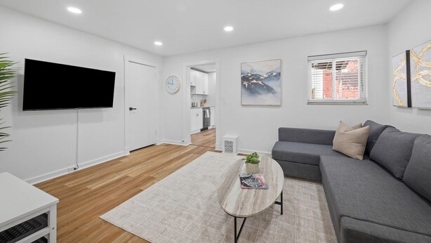 Una sala de estar moderna con un sofá gris, una mesa de centro y un televisor de pantalla plana montado en la pared.