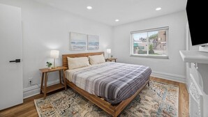 Un dormitorio con cama, mesitas de noche, alfombra y ventana con persianas.
