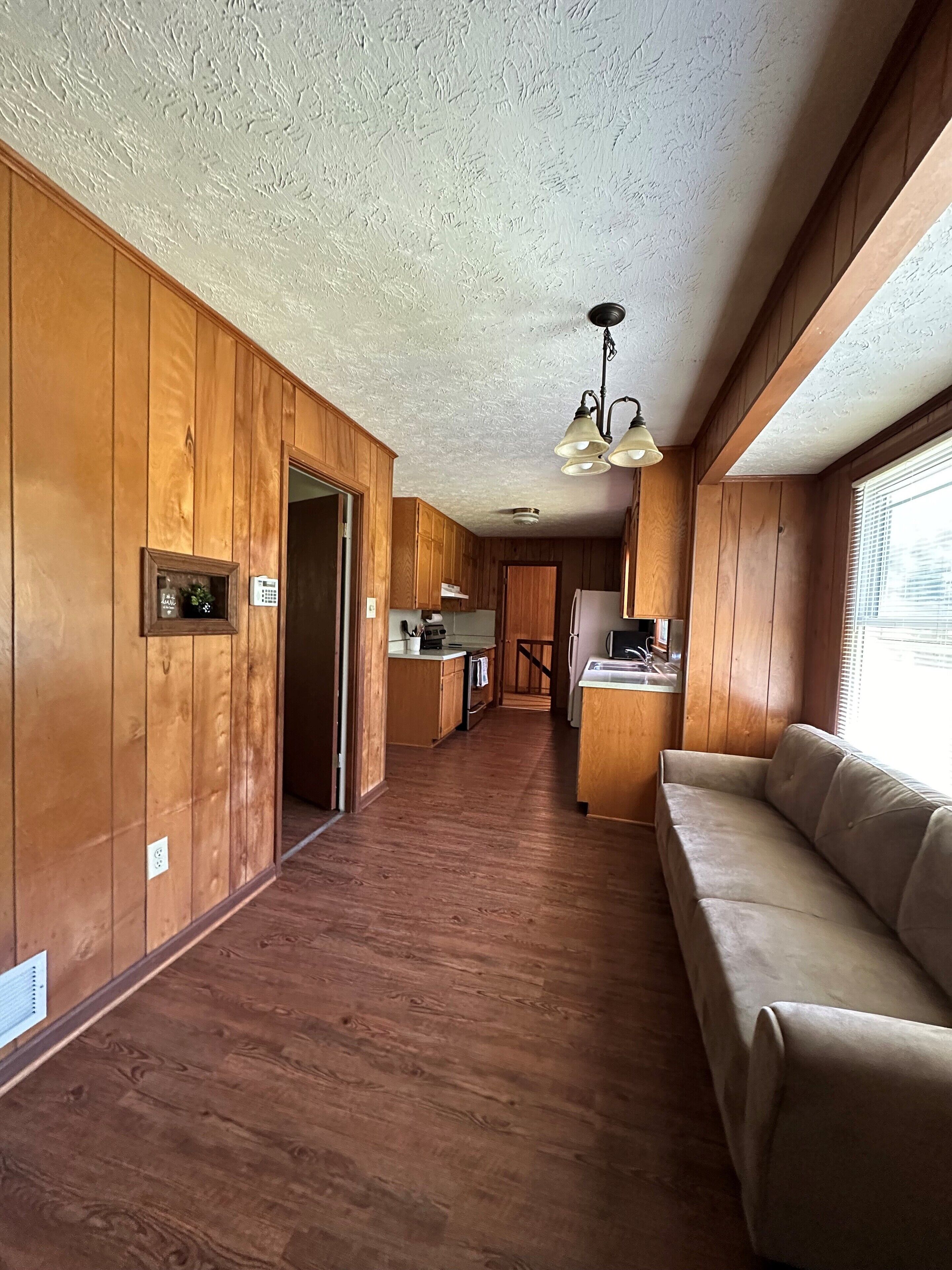 A kitchen with wooden cabinets, a dining area, and a sofa.