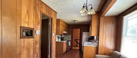 A kitchen with wooden cabinets, a dining area, and a sofa.