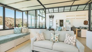 A modern living room with a large window, a sofa, and a built-in bench.