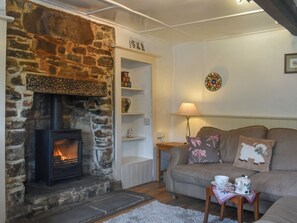 Una sala de estar acogedora con chimenea de piedra, un sofá con cojines estampados y una mesita con tetera y taza.
