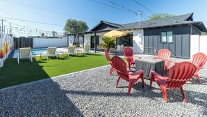 Une terrasse extérieure avec des chaises rouges, une table et un parasol jaune.
