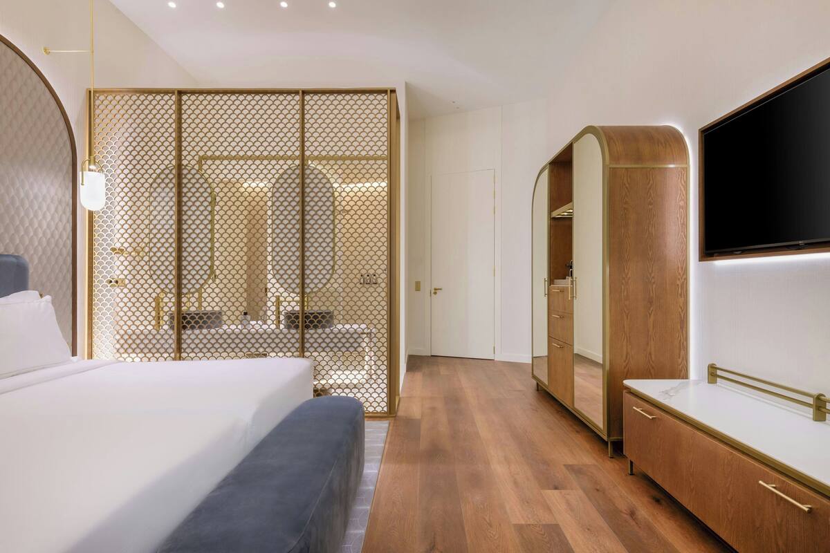 A modern bedroom with a bed, a wardrobe, and a TV.