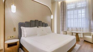 Una habitación de hotel moderna con una cama grande, una mesita de noche, una pequeña mesa redonda y un sofá.