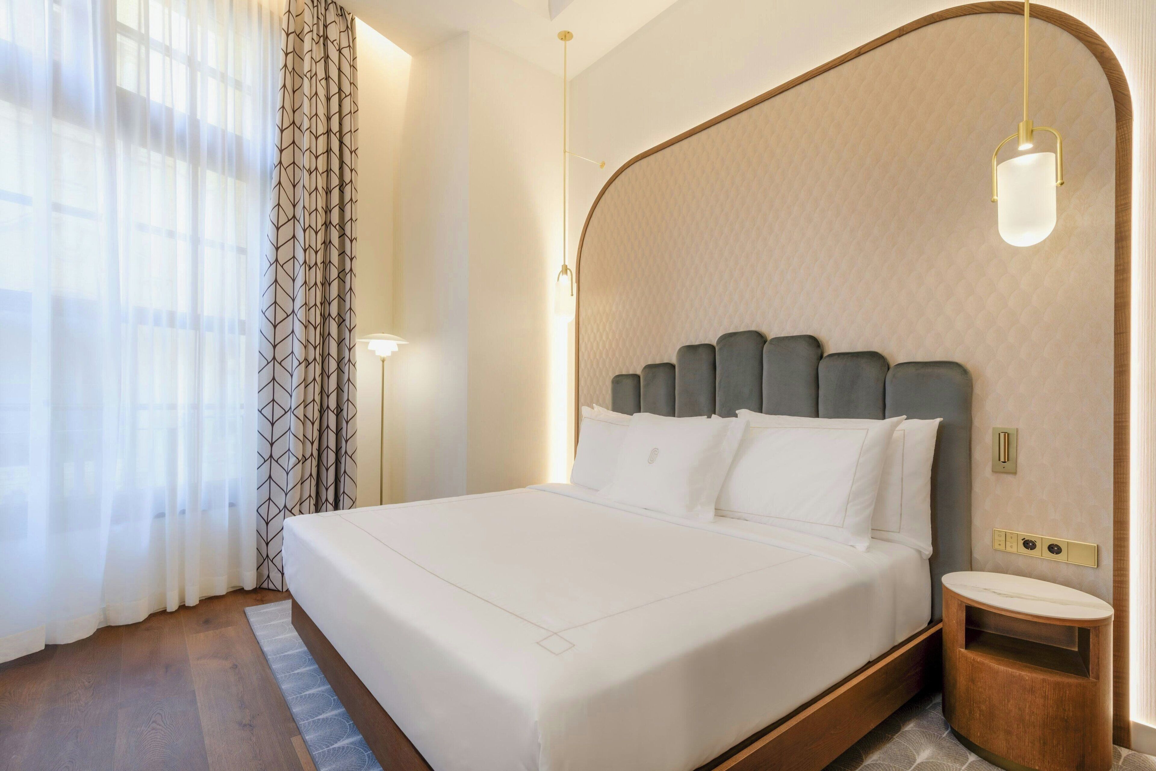 Una habitación de hotel moderna con una cama grande, una mesita de noche y una mesilla.