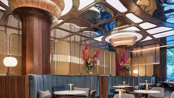 A modern interior with wooden columns, blue seating, and round tables.