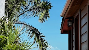 Un bâtiment en bois avec un auvent rouge, un palmier et une vue sur la mer.
