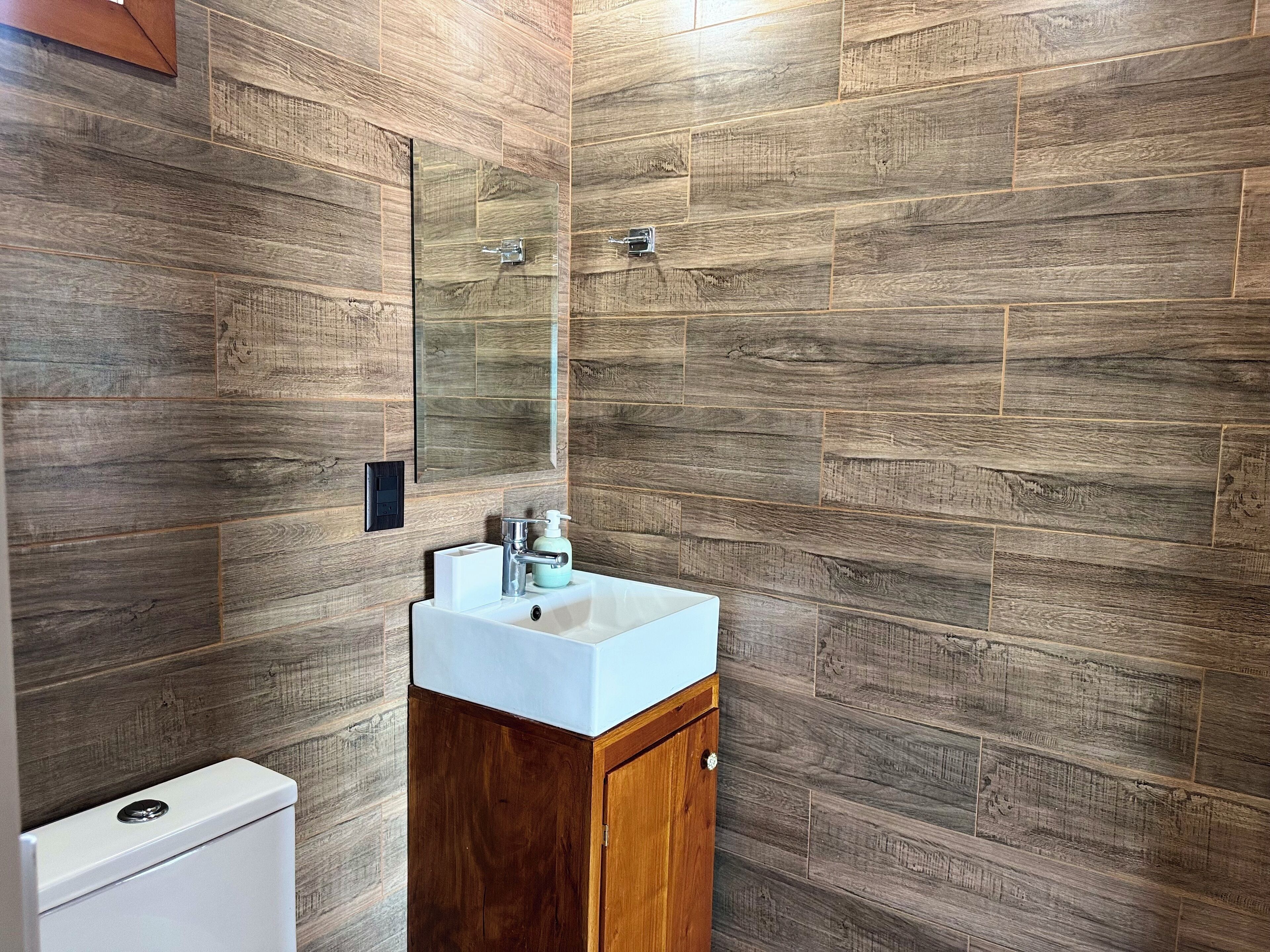 A bathroom with a wooden wall design, a white sink, and a mirror.