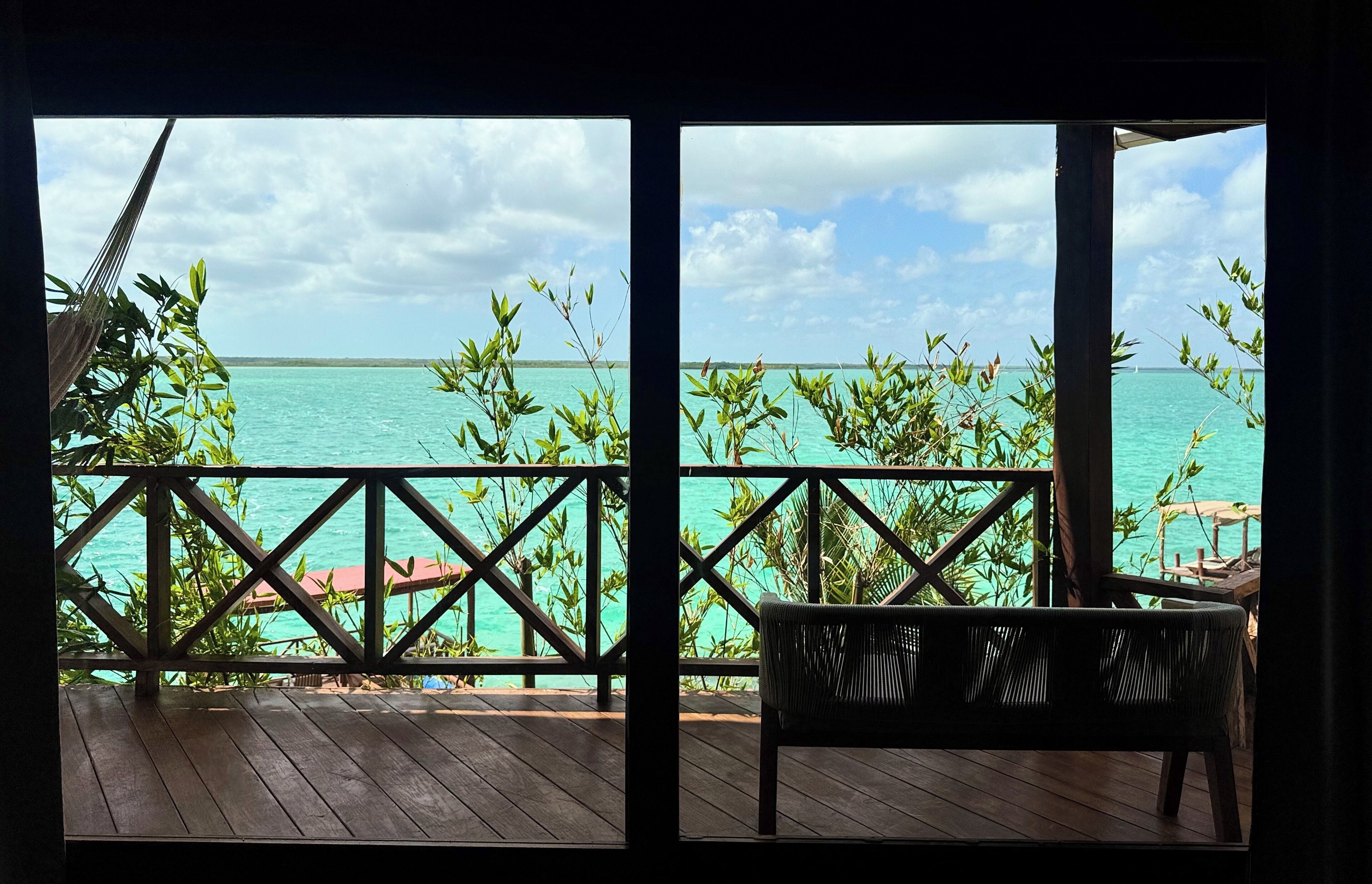 A wooden deck with a view of turquoise water and a clear sky.