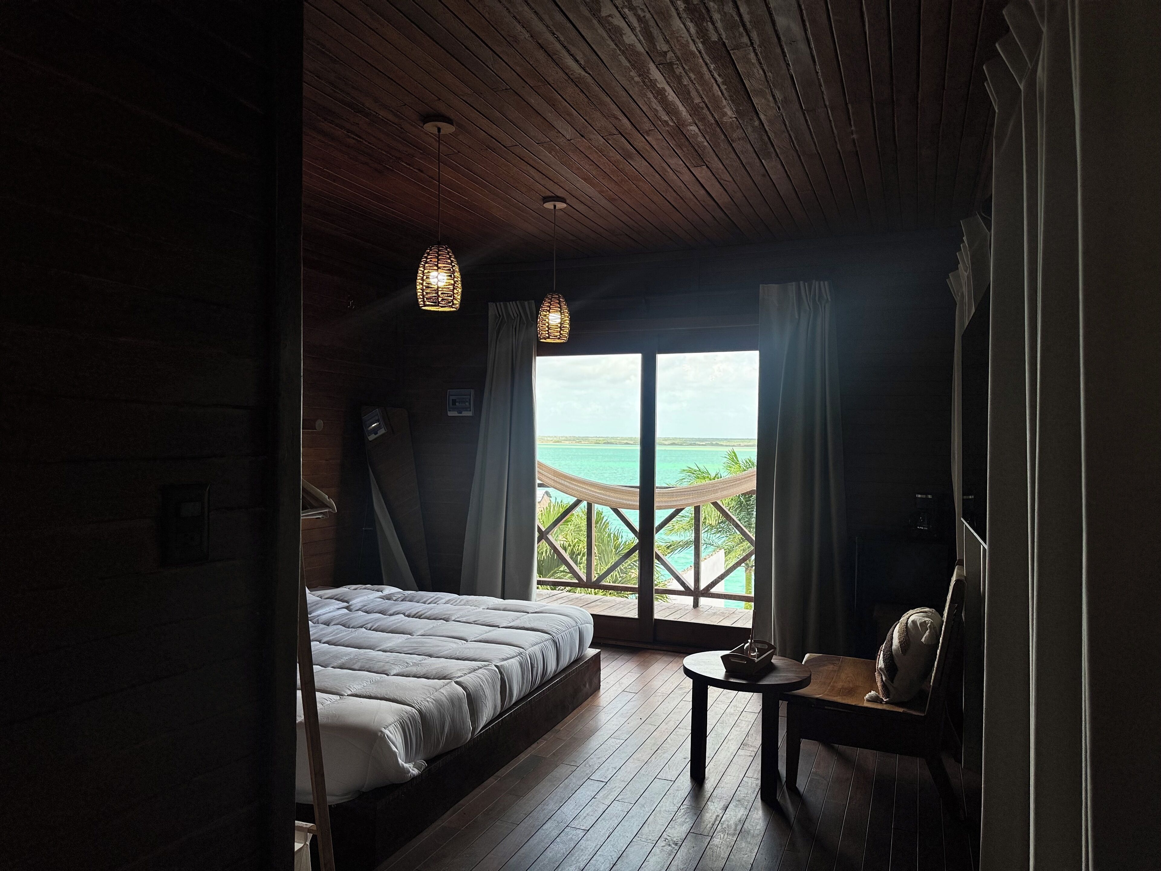 Une chambre avec un lit, une petite table et une vue sur l’océan.