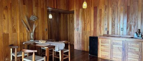 A wooden interior with a dining table, chairs, and a kitchen area.