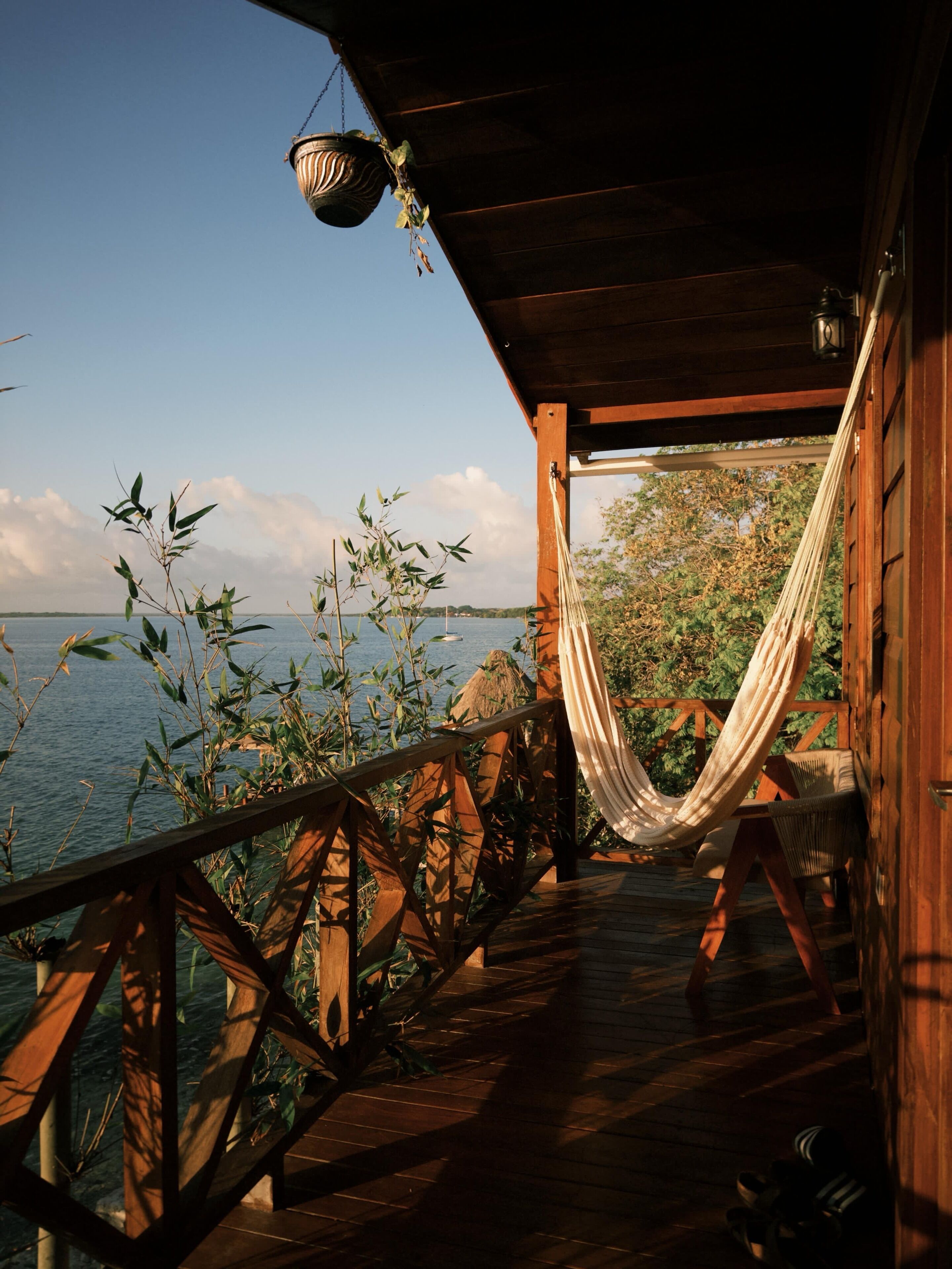 A wooden deck with a hammock, overlooking a body of water.