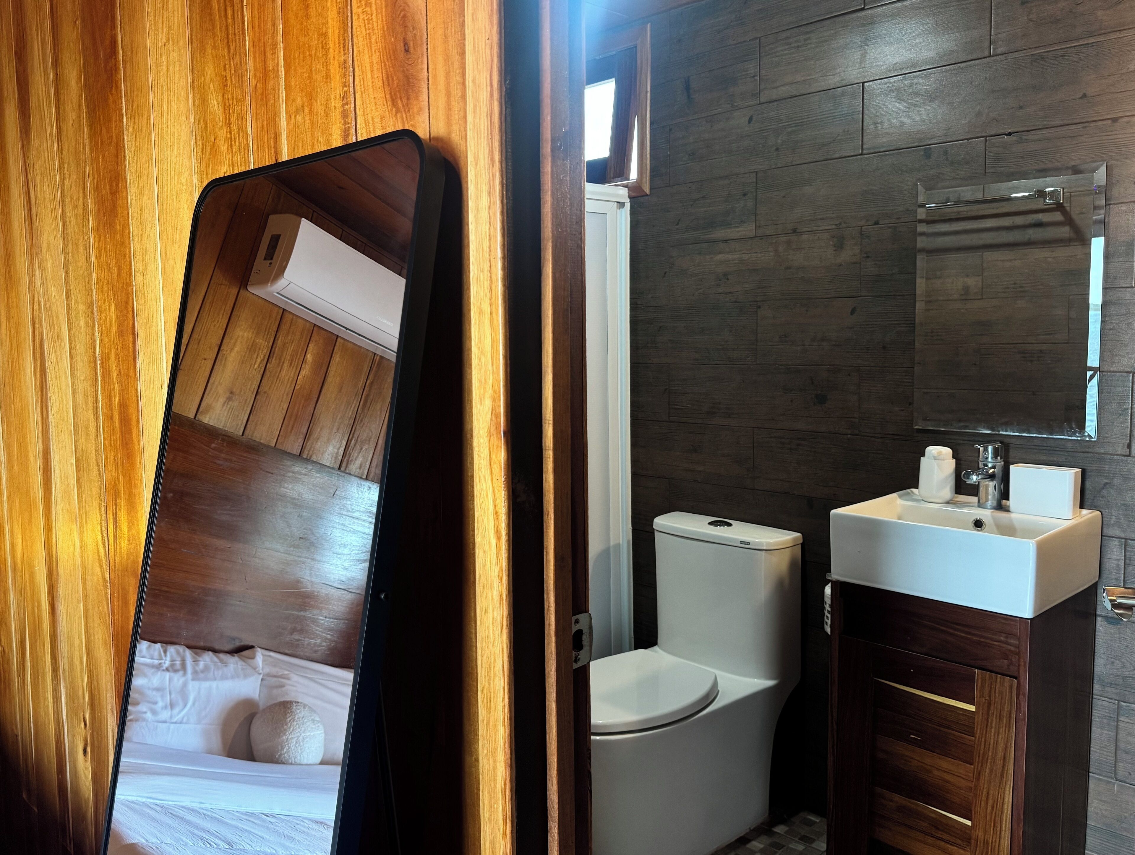 Een badkamer met toilet, wastafel en spiegel.