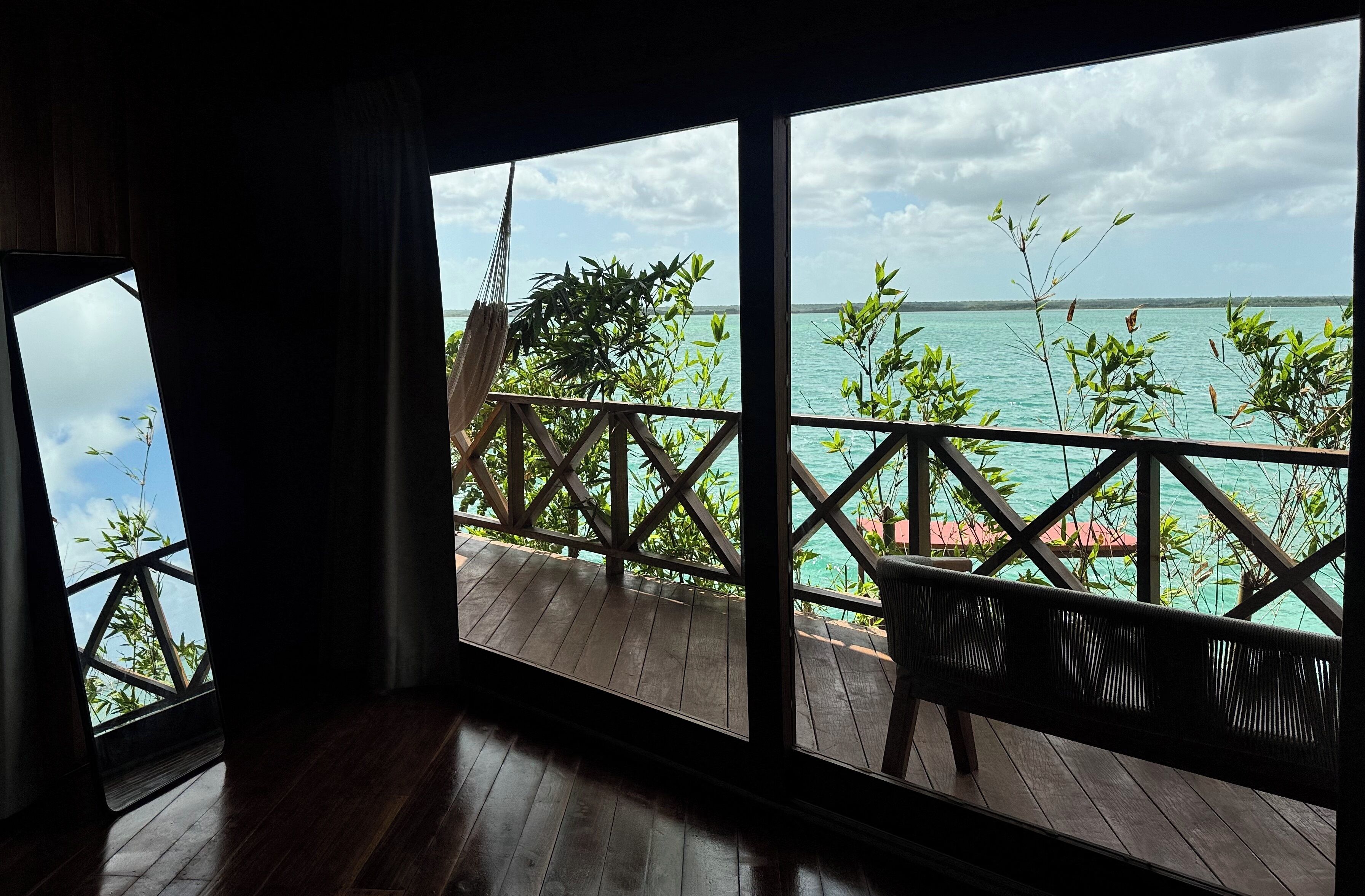 A wooden deck with a railing overlooking a turquoise sea and a clear sky.