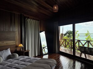 A bedroom with a large bed, wooden ceiling, and a view of the sea through a balcony. - Hotel Maria Isabel Bacalar (Bacalar)