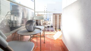 A small balcony with a table, chairs, and a decorative vase.
