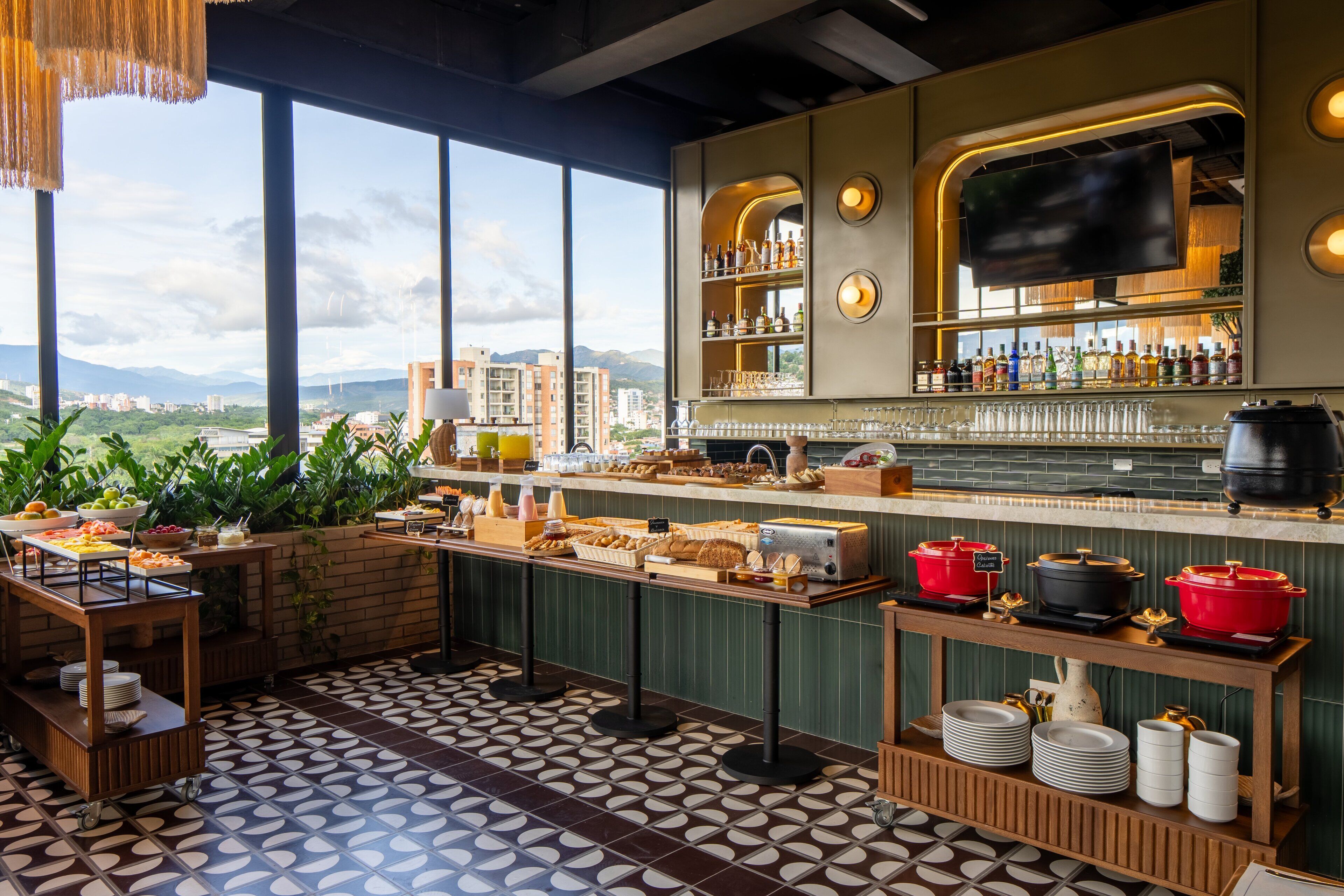 A bar area with a buffet, a TV screen, and a view of the city.