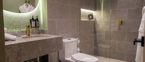 A modern bathroom with a marble sink, a toilet, and a glass-enclosed shower.