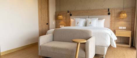 Un dormitorio moderno con una cama, un sofá, una mesita de madera y dos lámparas de noche.