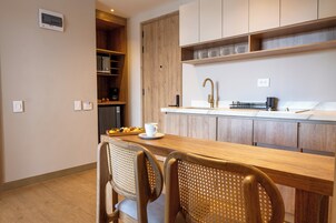 Una cocina moderna con armarios de madera, horno empotrado y un comedor con dos sillas y una mesa.