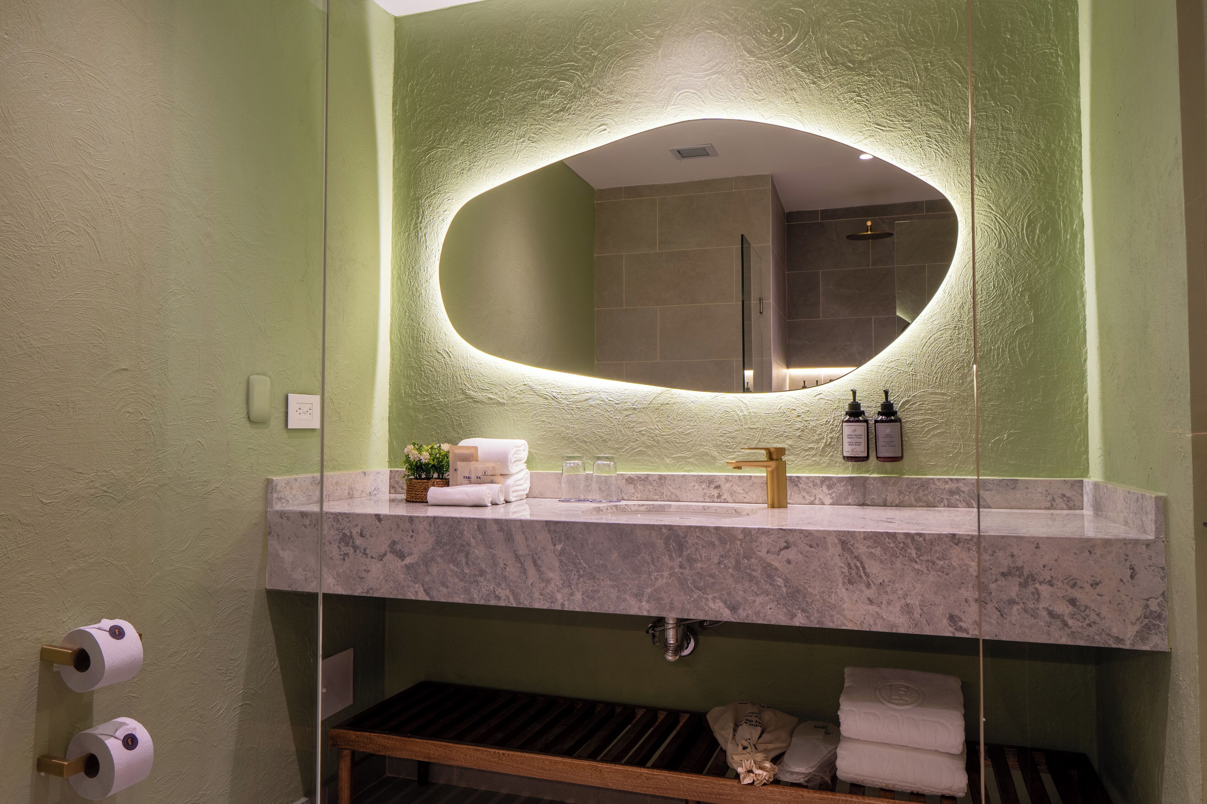 Une salle de bain avec un lavabo en marbre, un grand miroir et un porte-serviettes.