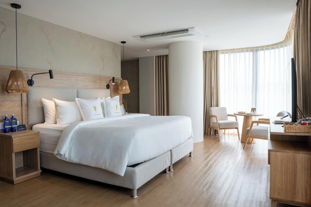 Ein modernes Hotelzimmer mit einem großen Bett, einem Schreibtisch und einem Sessel.