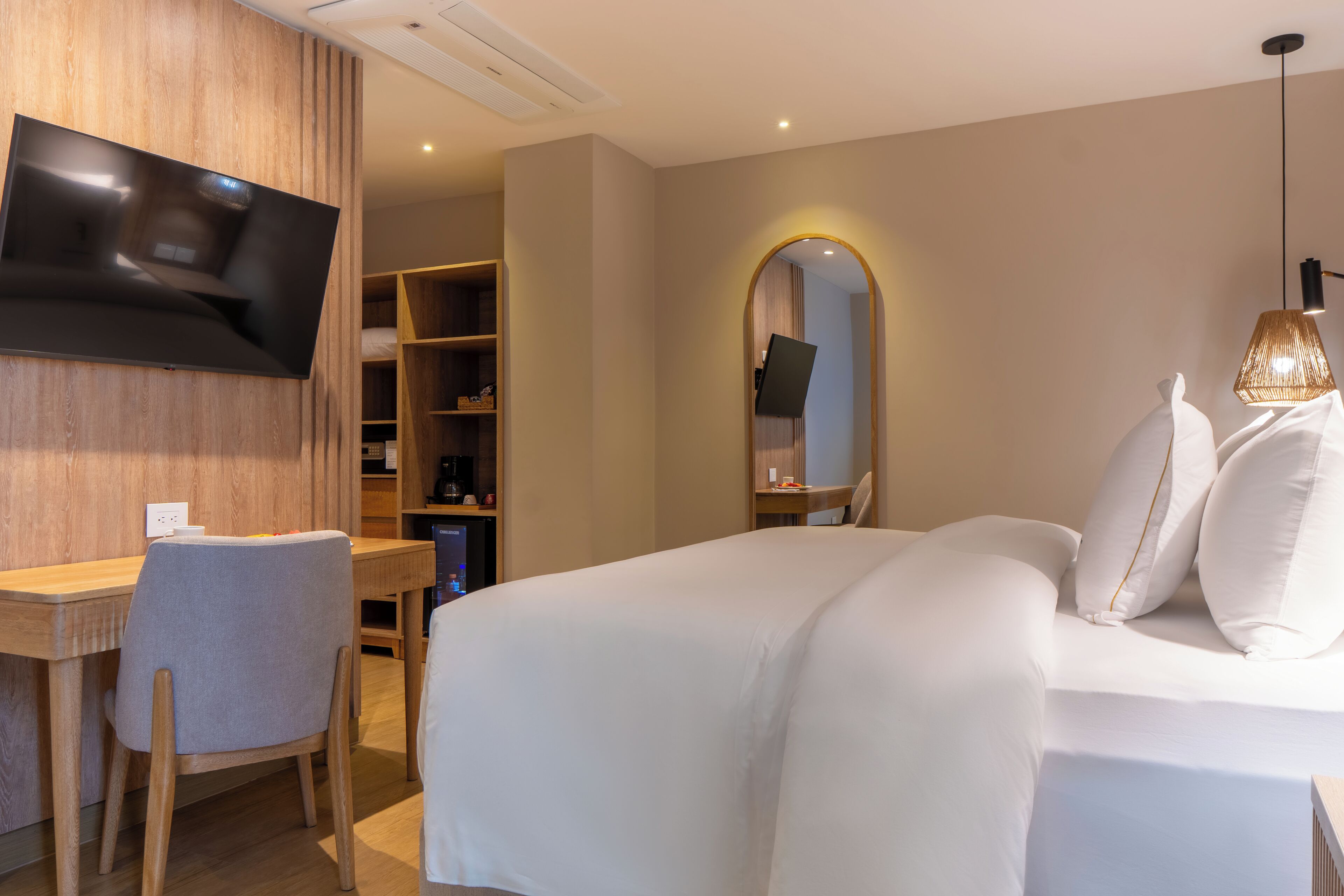Ein Hotelzimmer mit Bett, Schreibtisch, Stuhl, einem an der Wand befestigten Fernseher und einem Kleiderschrank.