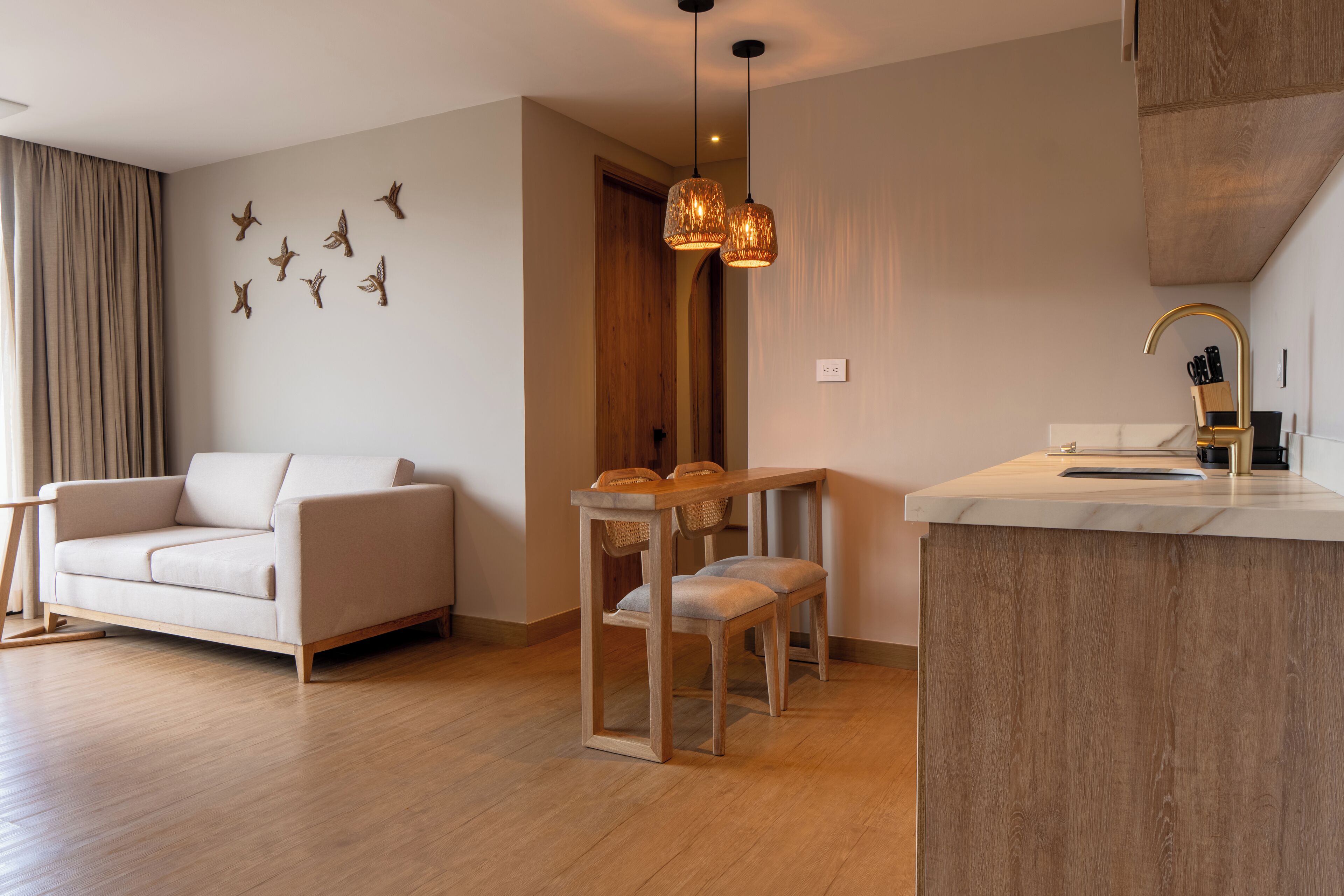 A modern living room with a sofa, a dining table with chairs, and a kitchen area with a countertop and sink.