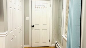 A hallway with a white door, a window with blinds, and a radiator. - 1-bedroom unit with Private Entrance/ Laundry/Kitchen/Parking (Abington)